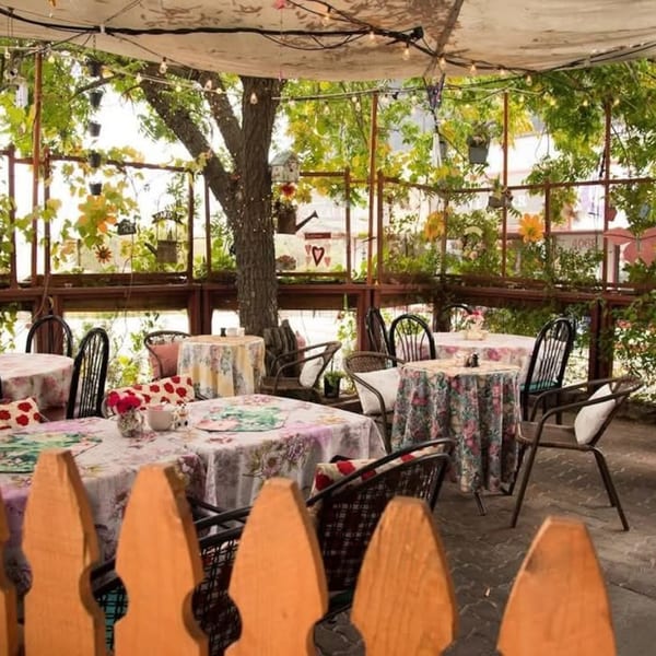 Charming outdoor patio at Crepe Town, with floral tablecloths, string lights, and lush greenery.