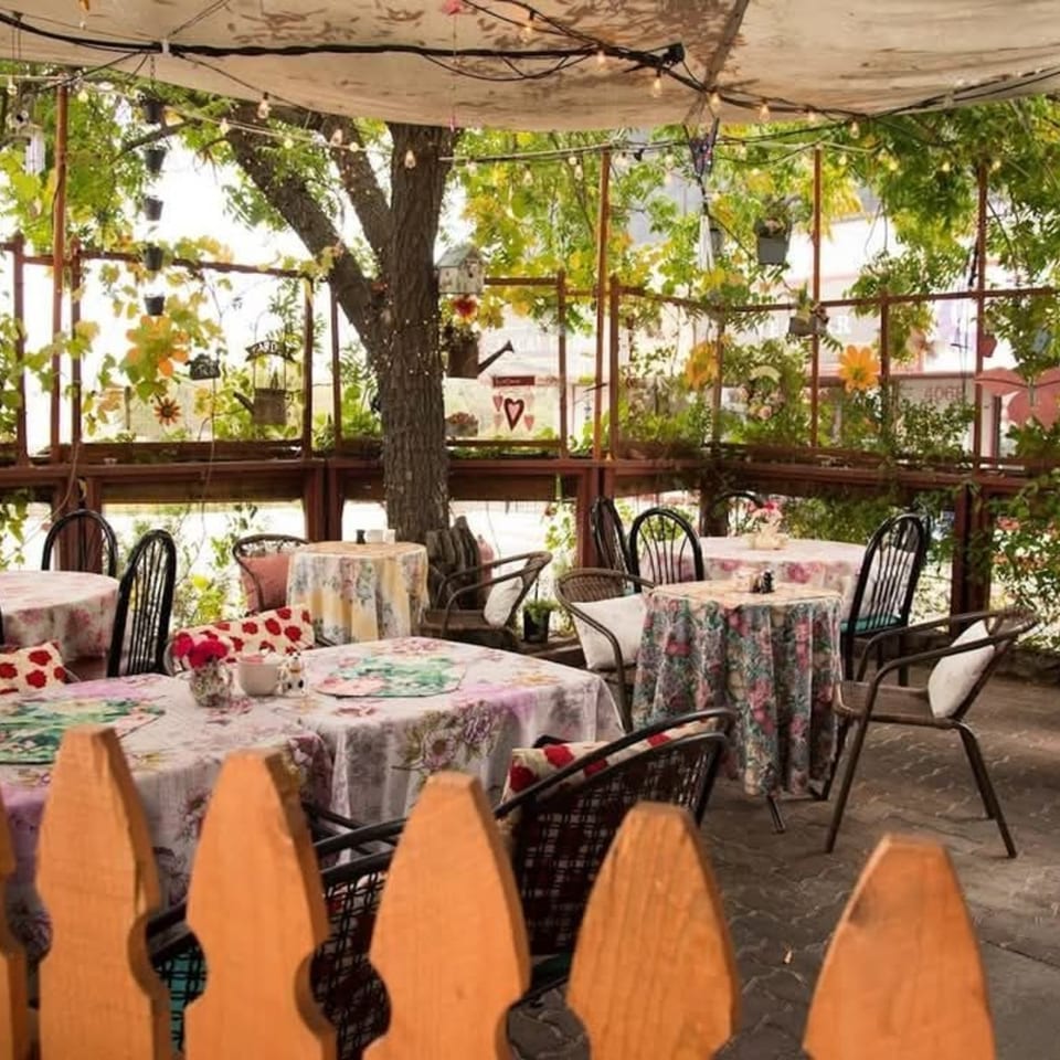 Charming outdoor patio at Crepe Town, with floral tablecloths, string lights, and lush greenery.