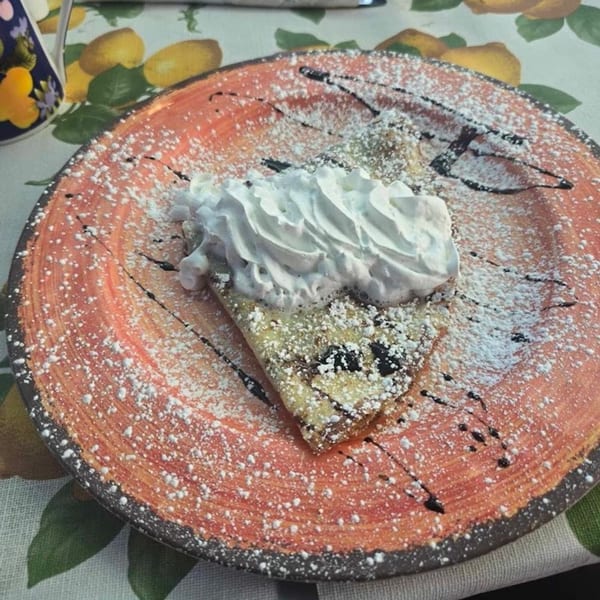 A Crepe Town European Café & Grill crepe with whipped cream, powdered sugar, and chocolate drizzle.